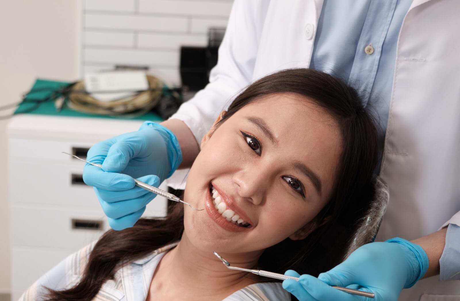 Dental patient smiling during a professional teeth cleaning appointment to prepare for whitening treatment at a dental office