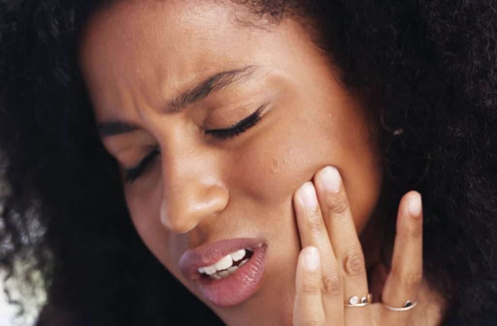 A woman putting holding her jaw due to TMJ pain
