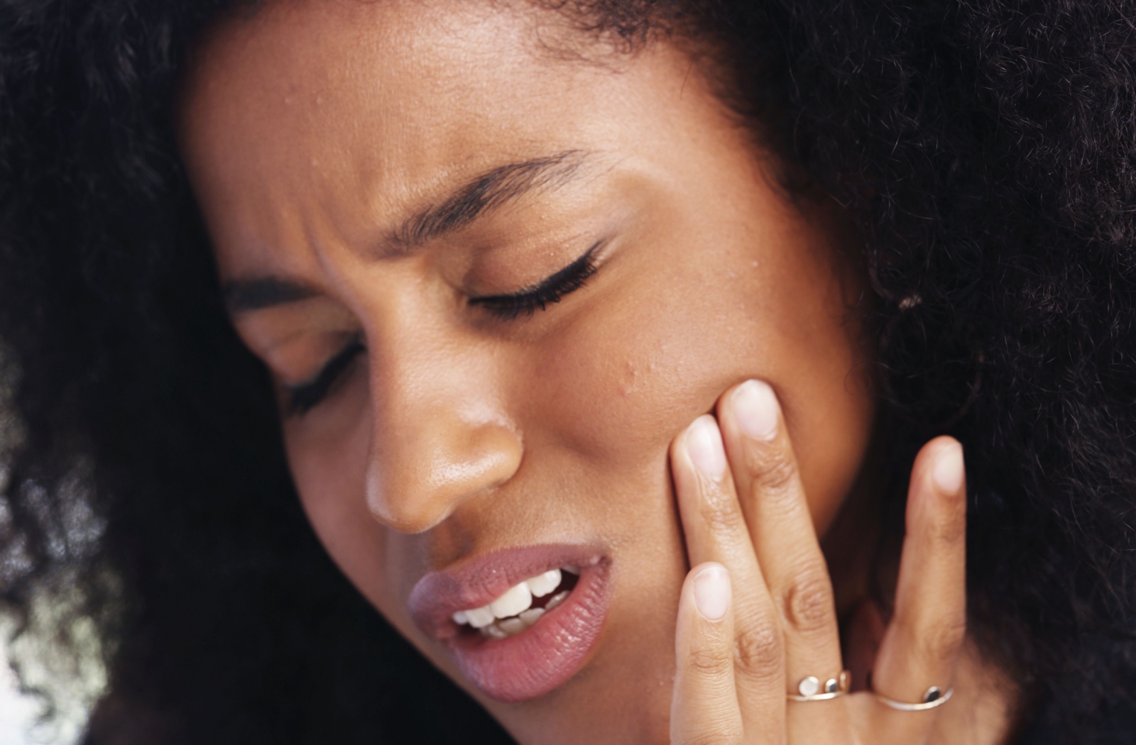 A woman putting holding her jaw due to TMJ pain