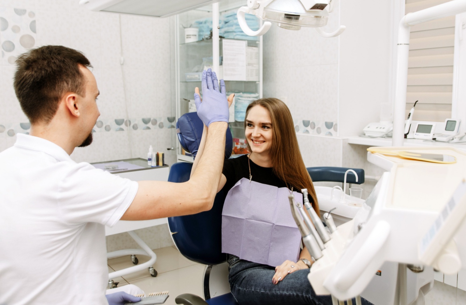 A dentist and a patient high-fiving in a dental office