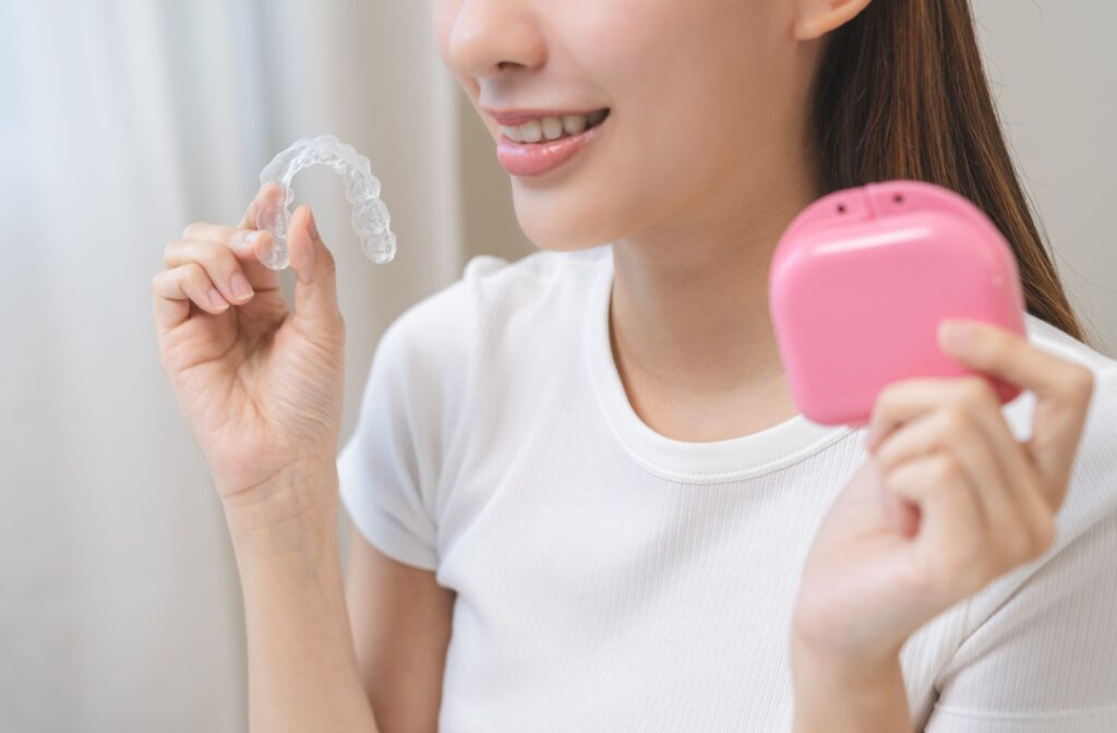 A person holding up their Invisalign clear aligner and their Invisalign case.